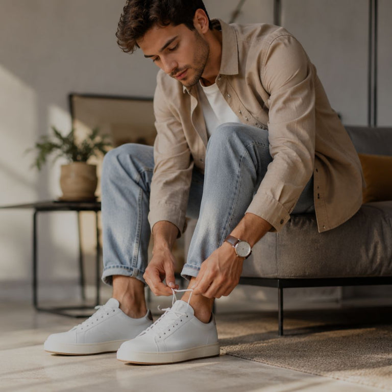 Man tying his shoes in a modern living room.